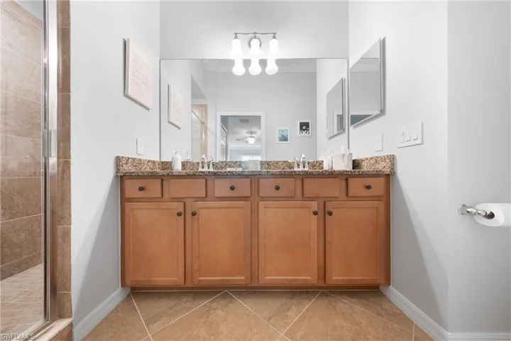 Bathroom with double vanity, a shower stall, and light tile patterned flooring