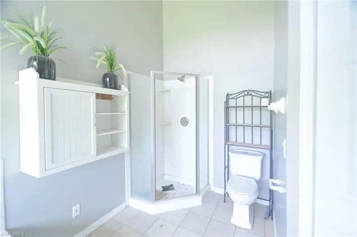 Bathroom with walk in shower, toilet, and tile patterned flooring