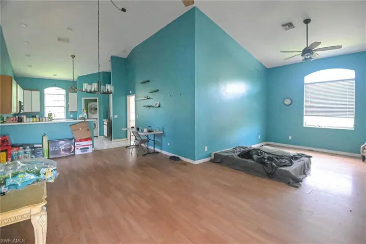 Workout area featuring ceiling fan, high vaulted ceiling, and light hardwood / wood-style floors