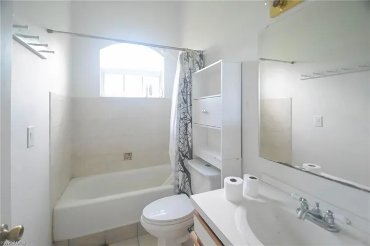 Full bathroom with shower / bath combo, tile patterned floors, vanity, and toilet