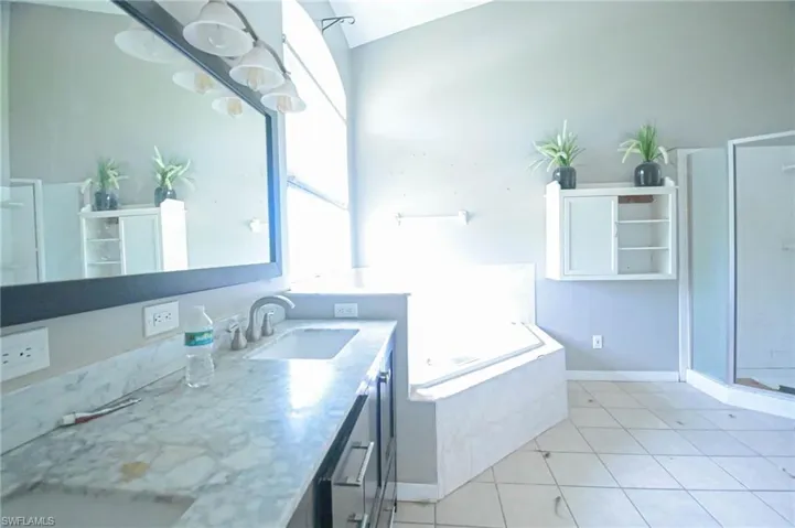 Bathroom with tile patterned floors, vanity, lofted ceiling, and independent shower and bath