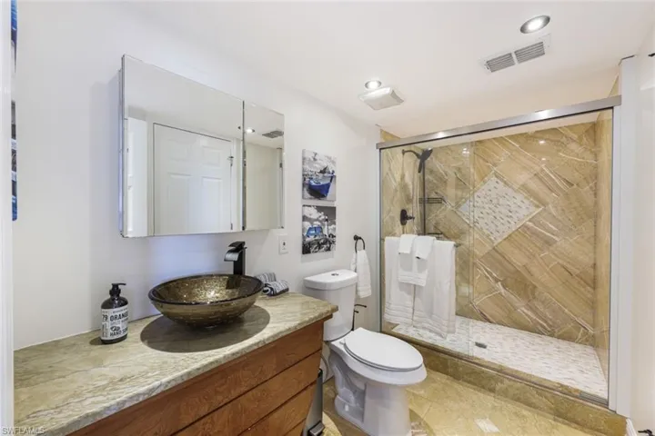 Bathroom featuring tile flooring, vanity, toilet, and a shower with door