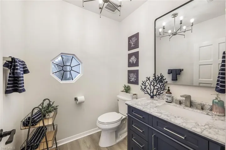 Bathroom featuring wood-type flooring, vanity, toilet, and a chandelier