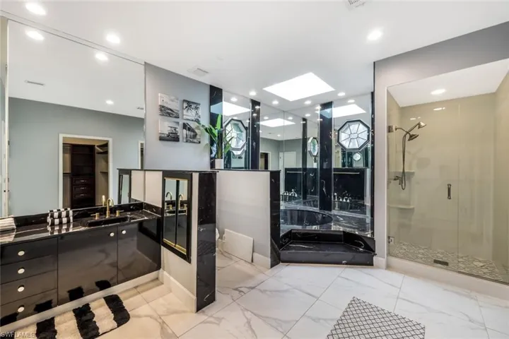 Bathroom featuring tile flooring, oversized vanity, an enclosed shower, and a skylight