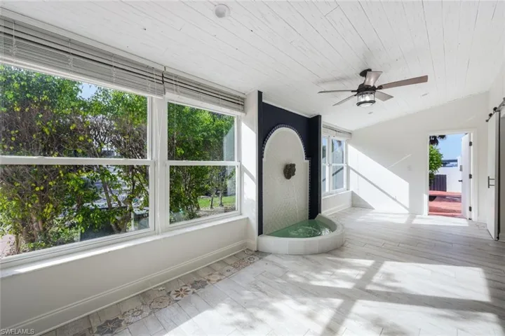 Unfurnished sunroom featuring a healthy amount of sunlight, wood ceiling, and ceiling fan