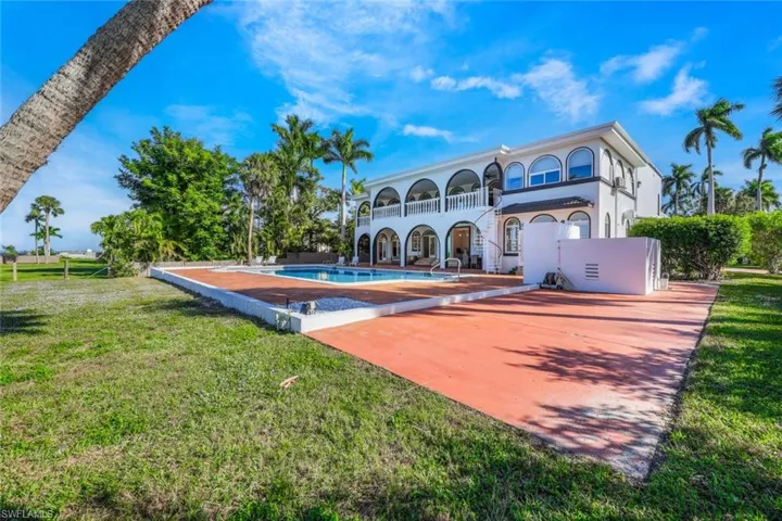 Rear view of property with a patio, a balcony, and a lawn