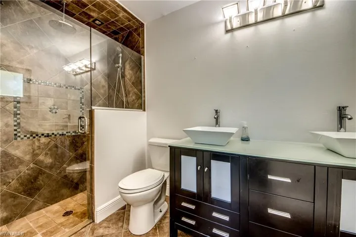 Full bath featuring double vanity, a stall shower, and tile patterned flooring