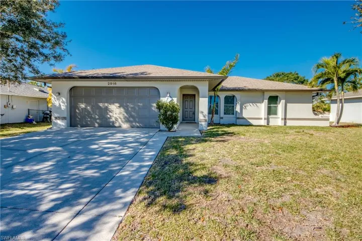 Ranch-style house with stucco siding, a front lawn, concrete driveway, an attached garage, and a shingled roof