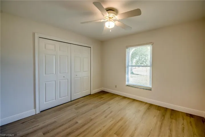 Unfurnished bedroom with light wood-style floors, a closet, and a ceiling fan
