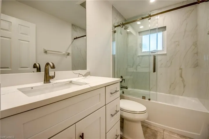 Bathroom with vanity, enclosed tub / shower combo, and light tile patterned floors