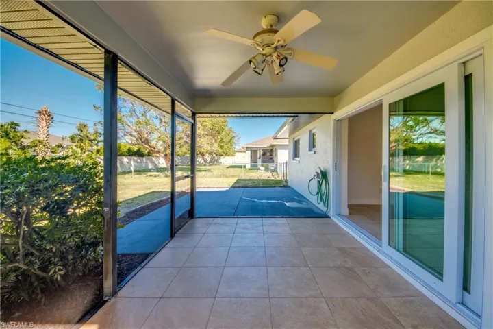 Unfurnished sunroom featuring ceiling fan and a patio
