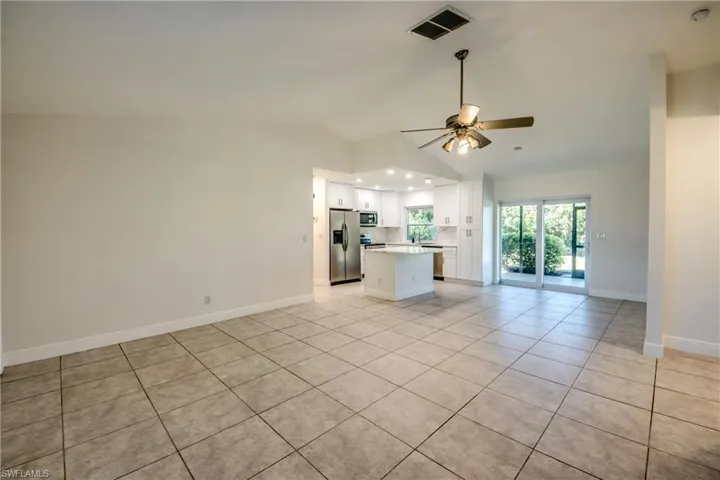 Unfurnished living room featuring light tile patterned flooring, vaulted ceiling, and a ceiling fan
