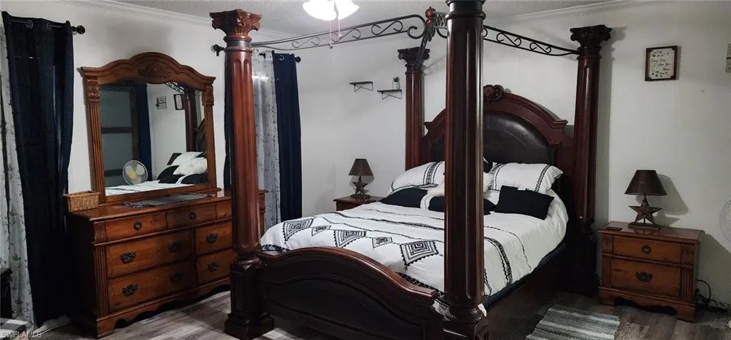 Bedroom with crown molding, a textured ceiling, and wood finished floors