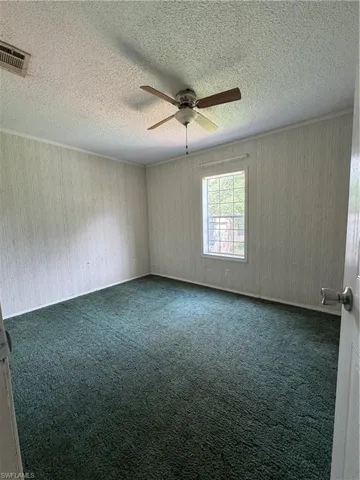 3rd Bedroom featuring ceiling fan, dark carpet, and a textured ceiling