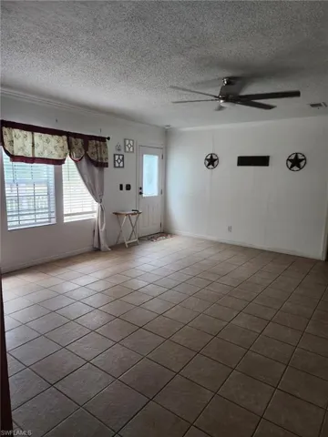Unfurnished room featuring ceiling fan, a textured ceiling, crown molding, and dark tile patterned flooring