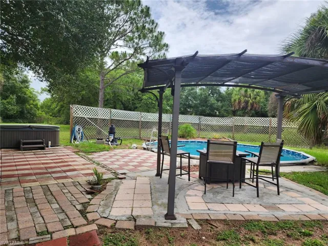 Fenced backyard featuring a hot tub, a pergola, and a patio