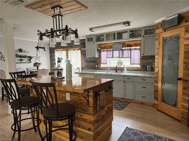 Kitchen featuring a textured ceiling, light countertops, gray cabinets, tasteful backsplash, and crown molding