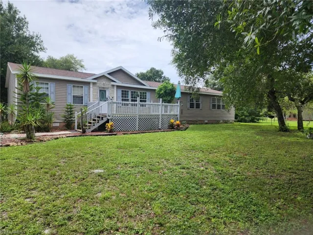 Back of house with crawl space, a wooden deck, and a yard