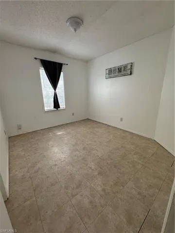 Extra bedroom #1 featuring a textured ceiling and tile patterned floors