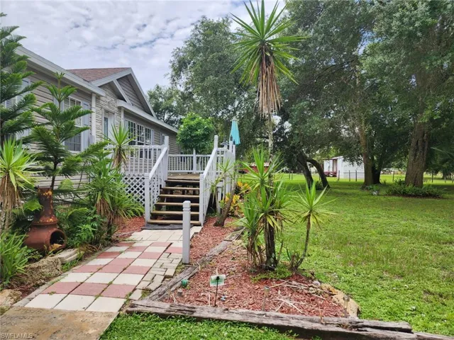 View of green lawn featuring a deck and stairs