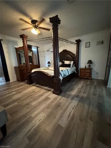 Master Bedroom featuring wood finished floors, ornamental molding, a textured ceiling, and a ceiling fan