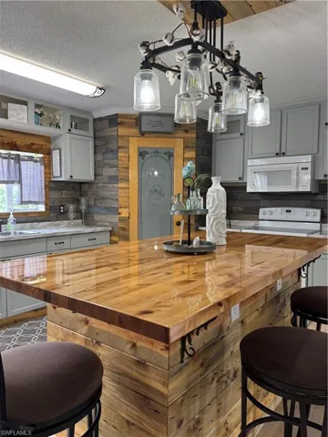 Kitchen with wooden counters, a textured ceiling, stove, a kitchen breakfast bar, and pendant lighting