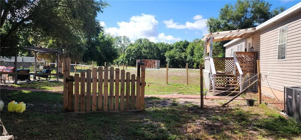View of yard featuring stairs, central AC unit, and fence