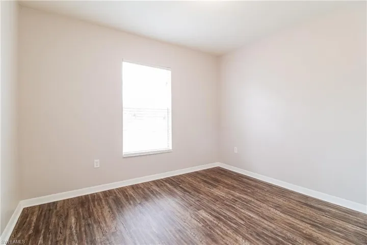 Empty room featuring dark wood-type flooring and baseboards