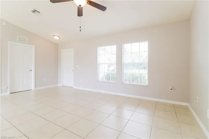 Spare room with ceiling fan, lofted ceiling, and light tile patterned floors