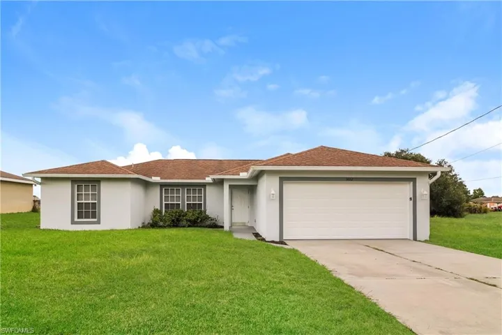 Ranch-style house featuring stucco siding, a garage, a front lawn, and driveway