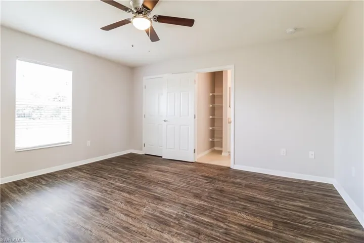 Unfurnished bedroom featuring dark wood-style flooring, a ceiling fan, and a closet
