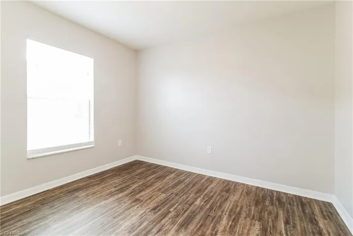 Empty room featuring baseboards and dark wood-style floors