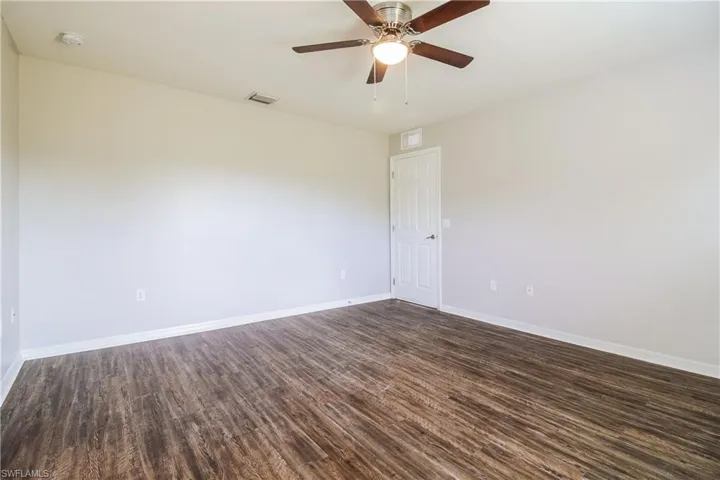 Empty room featuring ceiling fan and dark wood-type flooring