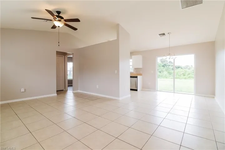 Unfurnished room with hanging lights, a ceiling fan, light tile patterned flooring, and vaulted ceiling