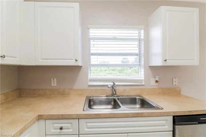 Kitchen featuring white cabinets, dishwasher, and light countertops