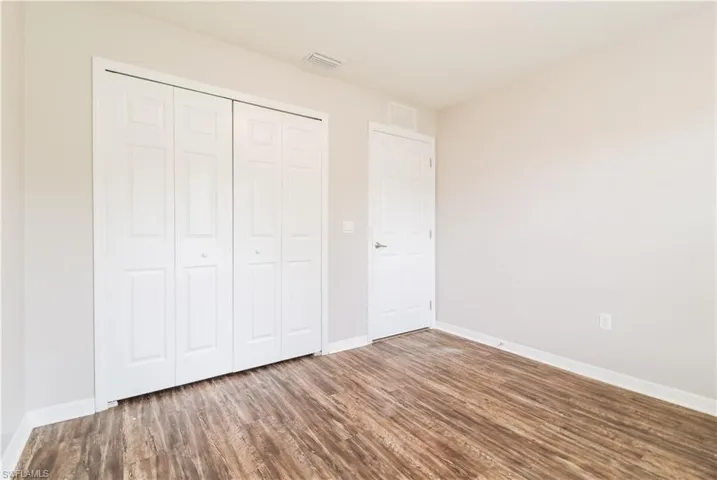 Unfurnished bedroom featuring wood finished floors and a closet