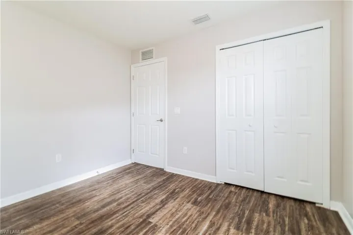 Unfurnished bedroom featuring a closet and dark wood-type flooring