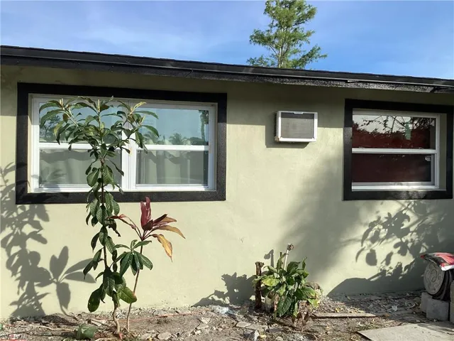 View of side of home featuring stucco siding and an AC wall unit