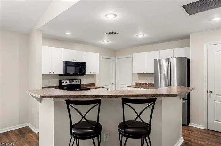 Kitchen featuring white cabinets, stainless steel appliances, and a breakfast bar area