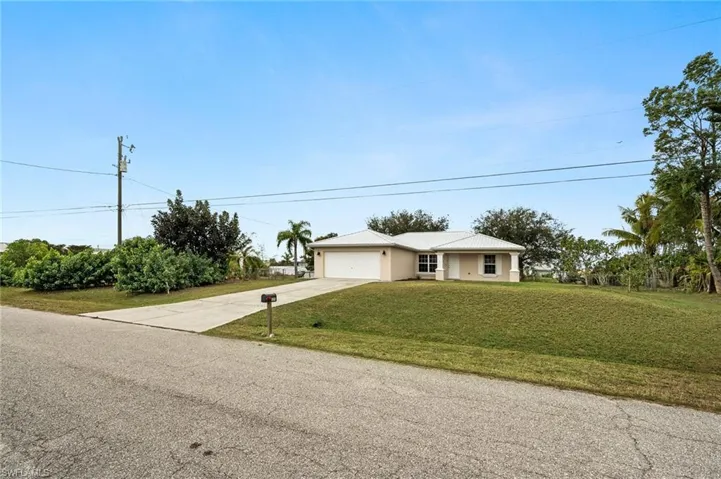 Single story home with a garage and a front lawn