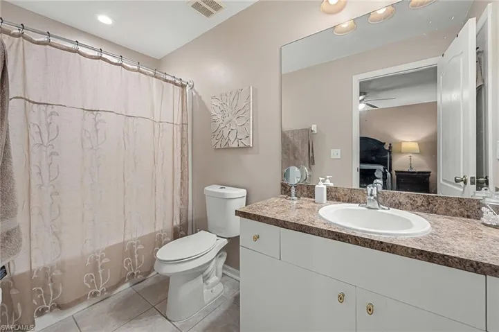 Full bathroom featuring ceiling fan, vanity, toilet, tile patterned floors, and shower / bath combo