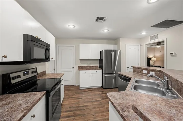 Kitchen with white cabinetry, stainless steel appliances, sink, dark hardwood / wood-style floors, and ceiling fan