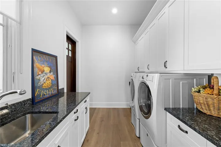 Kitchen with a chandelier, a breakfast bar, a kitchen island with sink, white cabinetry, and pendant lighting