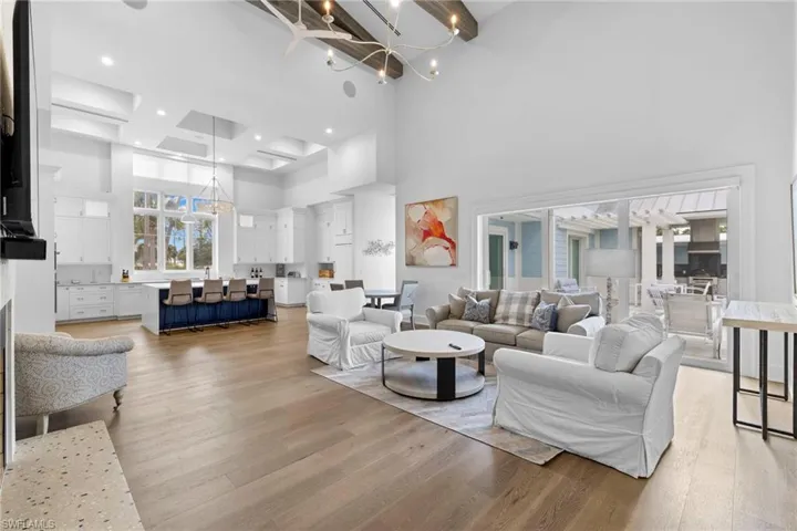 Living area featuring a chandelier, wood finished floors, a warm lit fireplace, and a towering ceiling