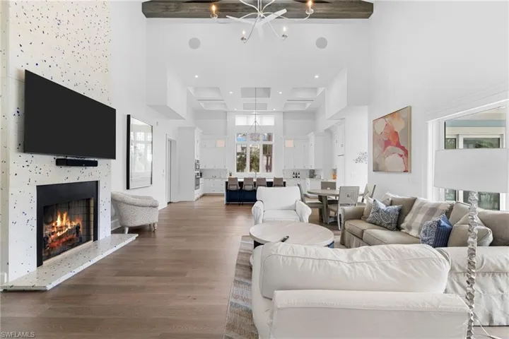 Living area featuring a towering ceiling, a warm lit fireplace, and wood finished floors