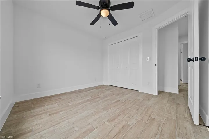 Unfurnished bedroom featuring wood finish floors, a closet, and a ceiling fan