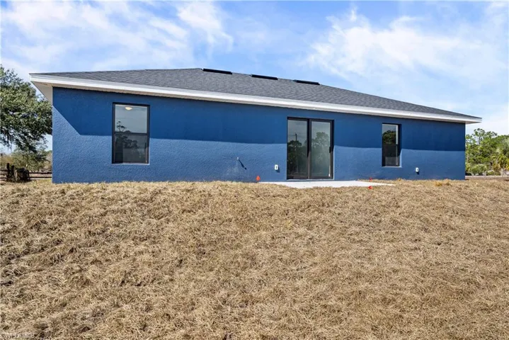 Rear view of house with stucco siding and a lawn