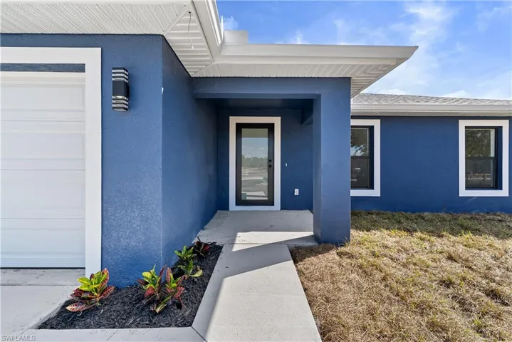 Entrance to property with stucco siding and a lawn