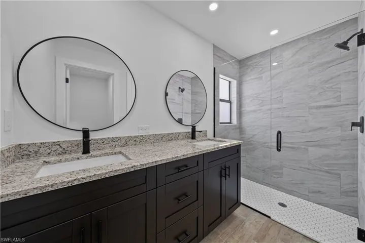 Bathroom with double vanity, a shower stall, recessed lighting, and light wood-style flooring