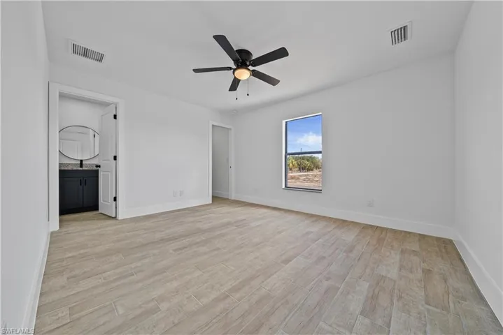 Unfurnished bedroom with light wood finished floors, a ceiling fan, and ensuite bathroom
